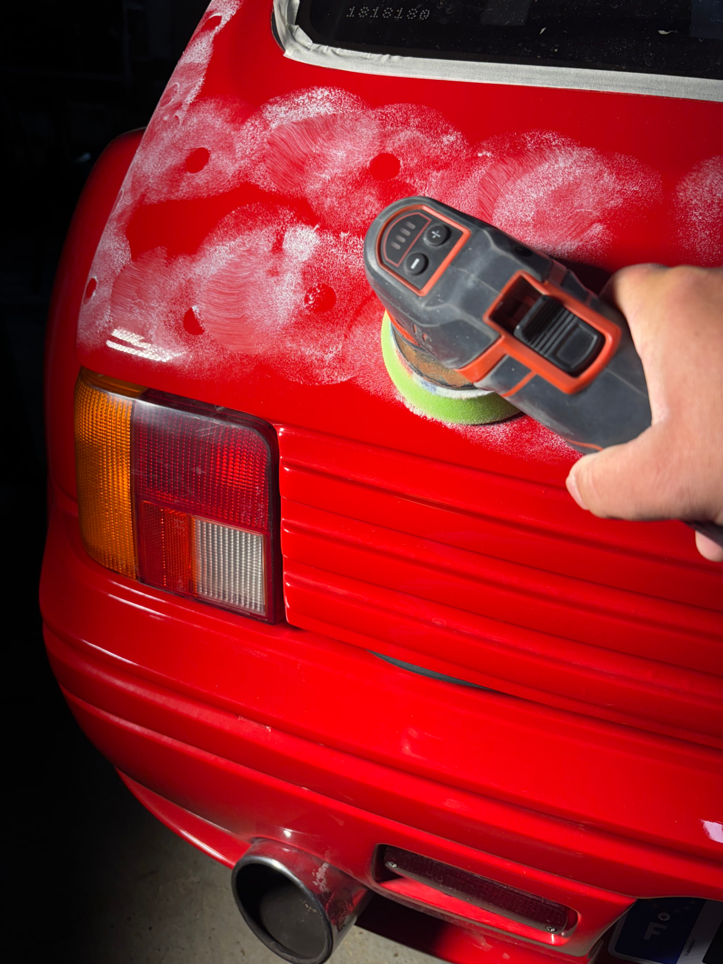 Polissage d'une carrosserie rouge à la polisseuse orbitale